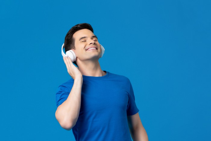 Relaxing young man listening to music from headphones with eyes closed